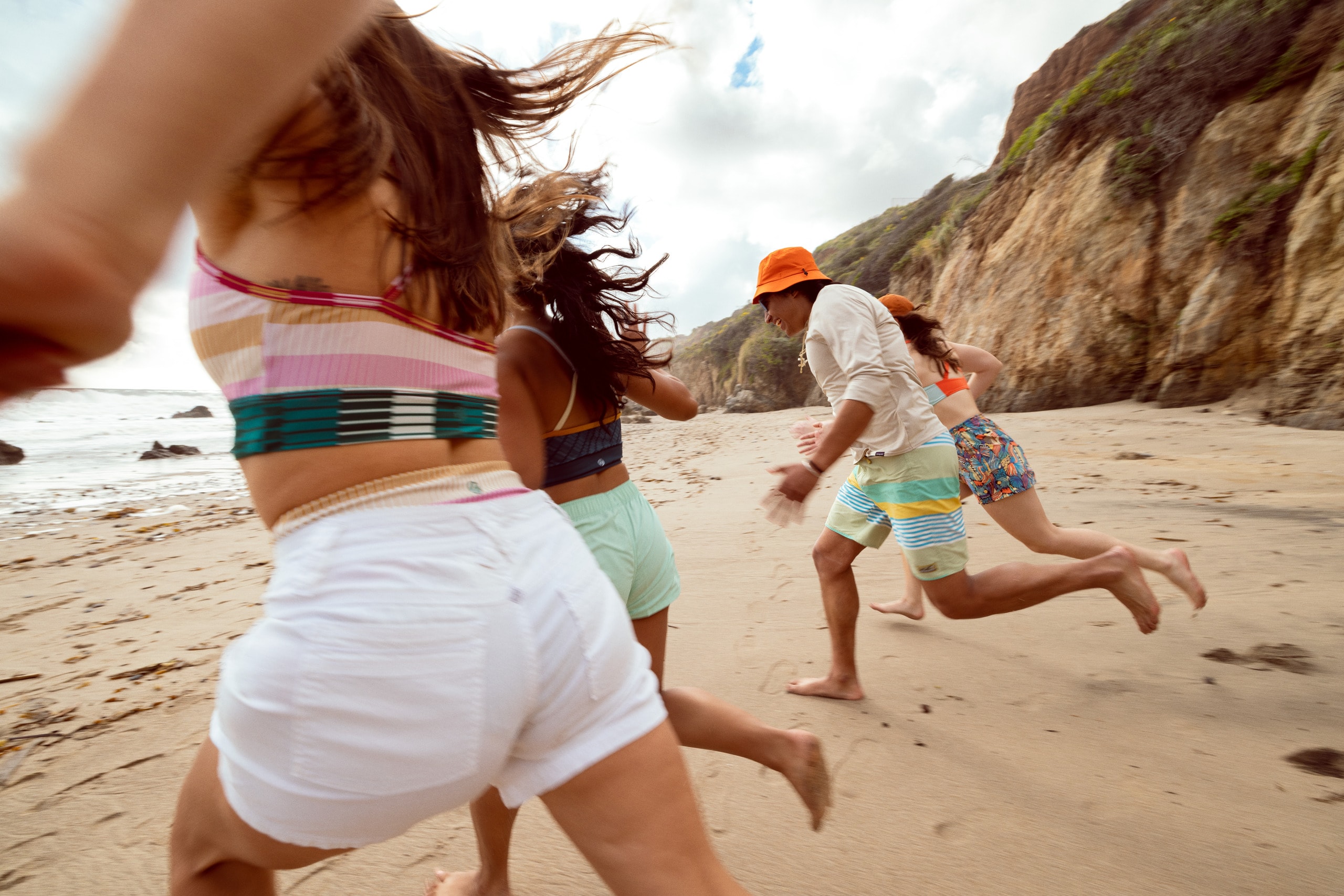 Four people wearing swimwear race to the beach