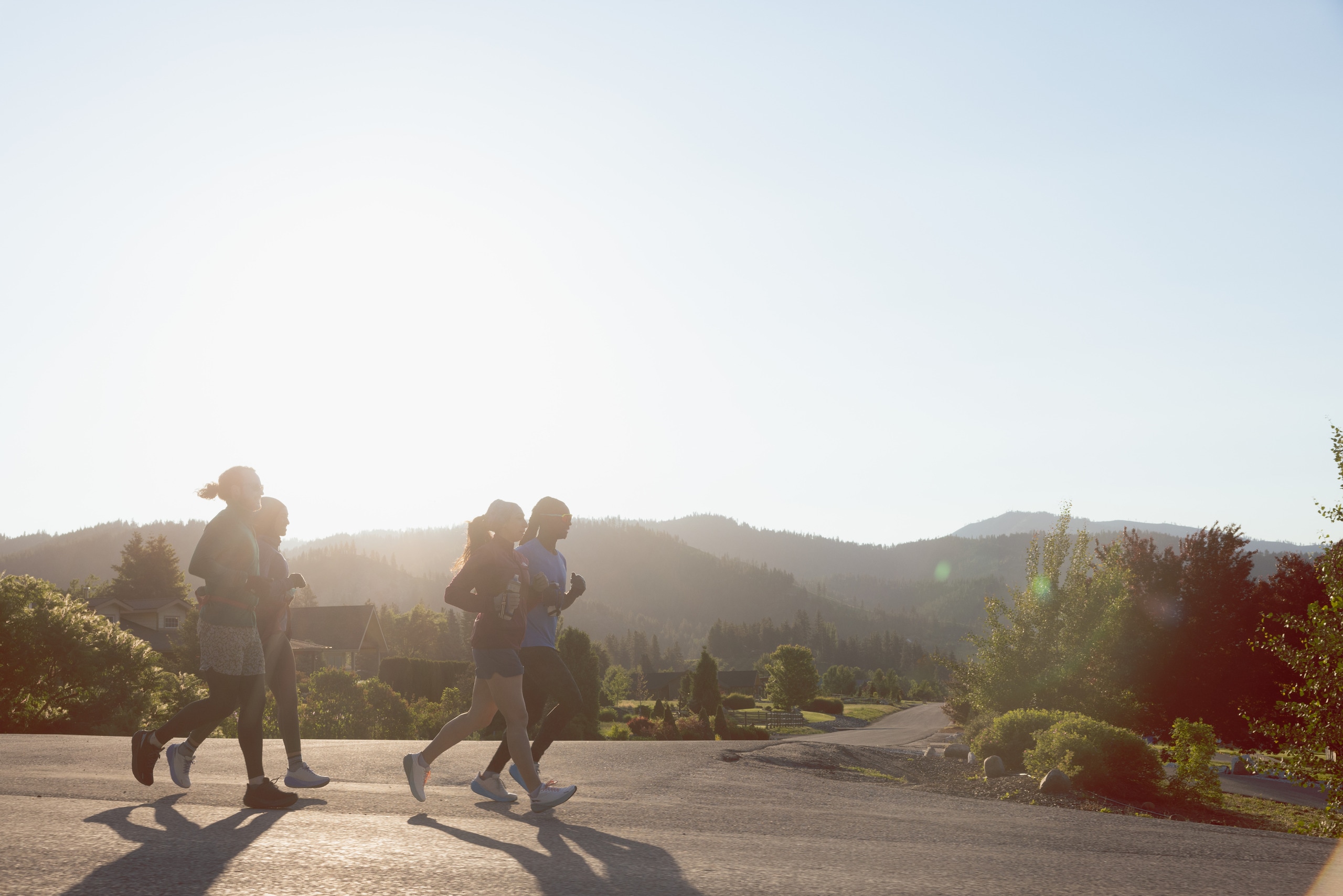 A group of people running down a road, with mountains behind them
