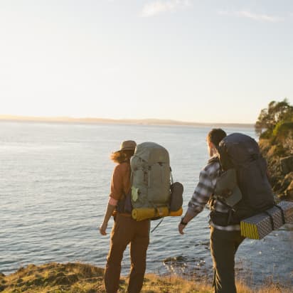 two backpackers walking along a coastal cliff