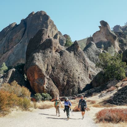three hikers walking on a desert trail