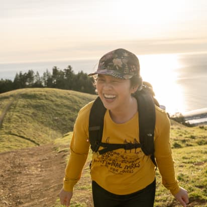 a hiker laughing on a hill near the sea