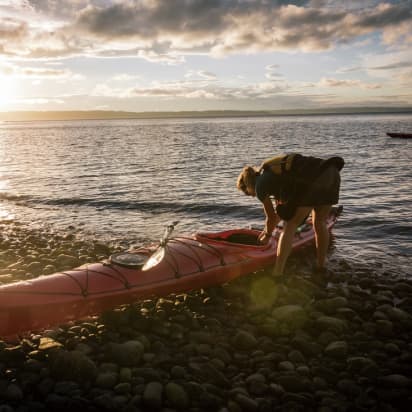 a kayaker preparing a kayak on a beach