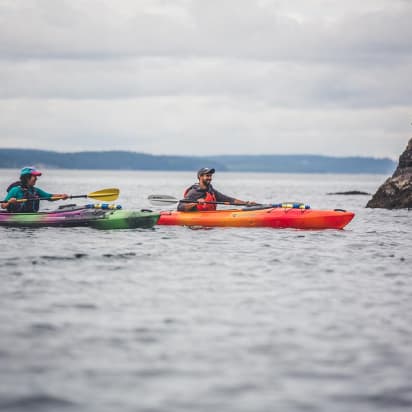 two kayakers paddling near rocks