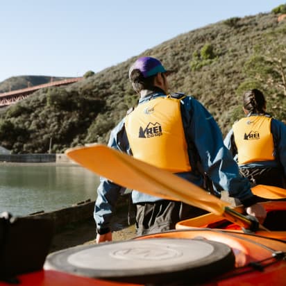 a group of kayakers carrying oars and a kayak