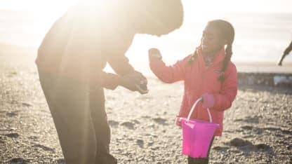 A child holds a rock on a beach