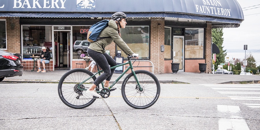 mulher de bicicleta através de bairro