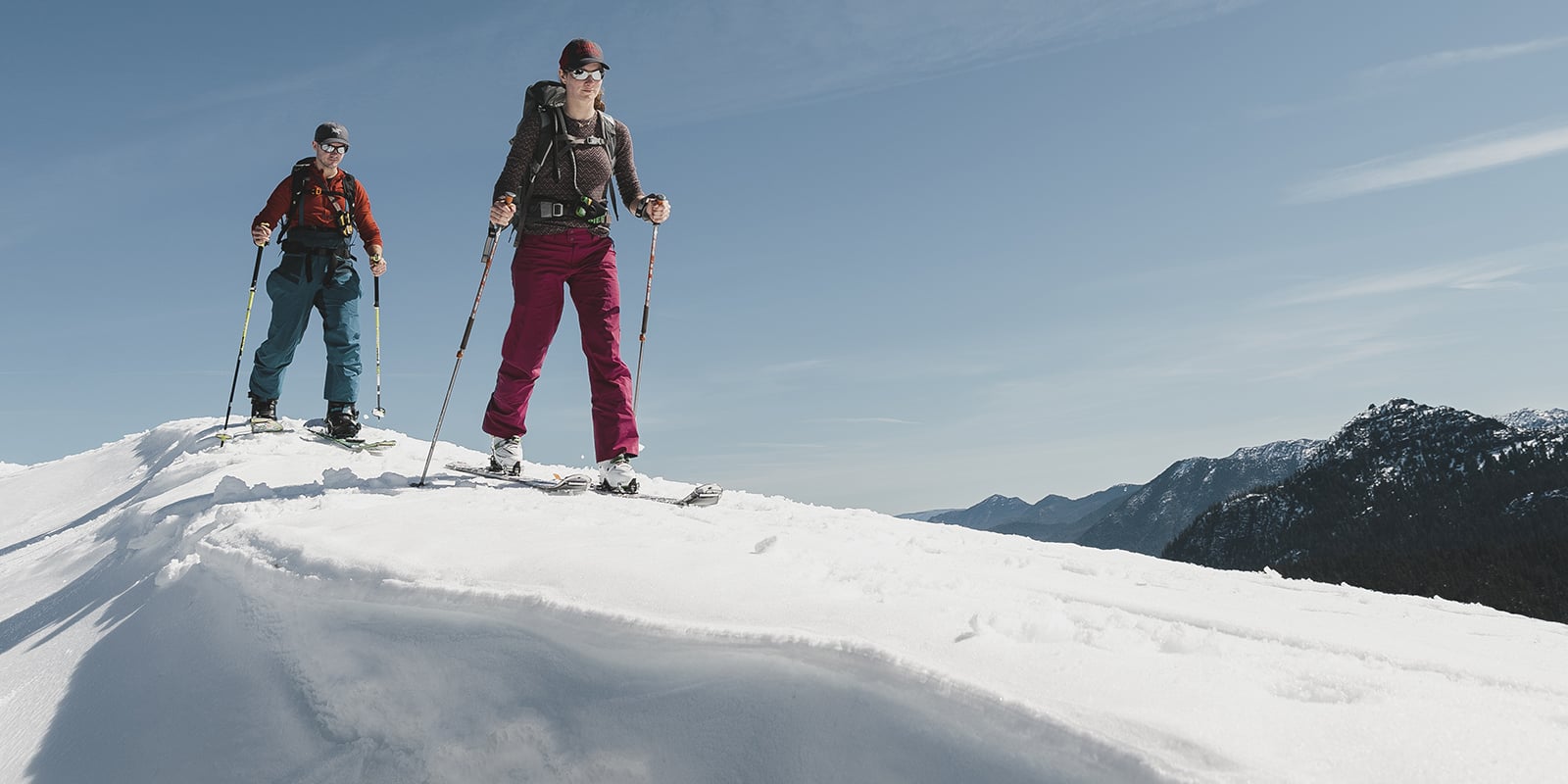 two backcountry skiers on a steep snowy ridge