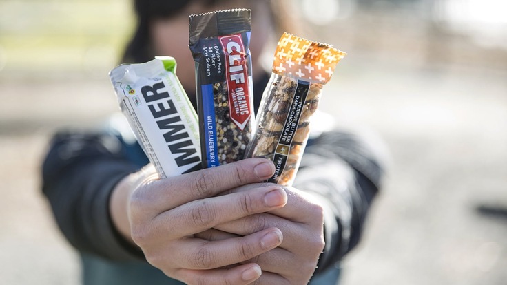 Person holding three energy bars