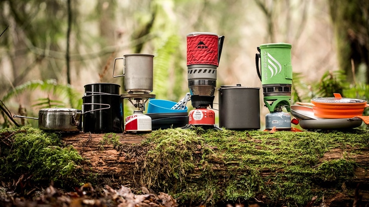 Backpacking stoves and cooking pots on a log