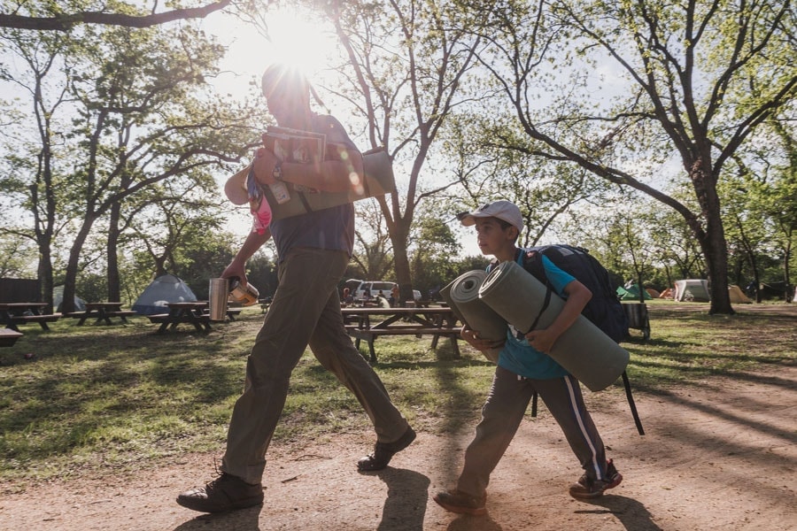 Father and son walking though a campground with tents in the background.