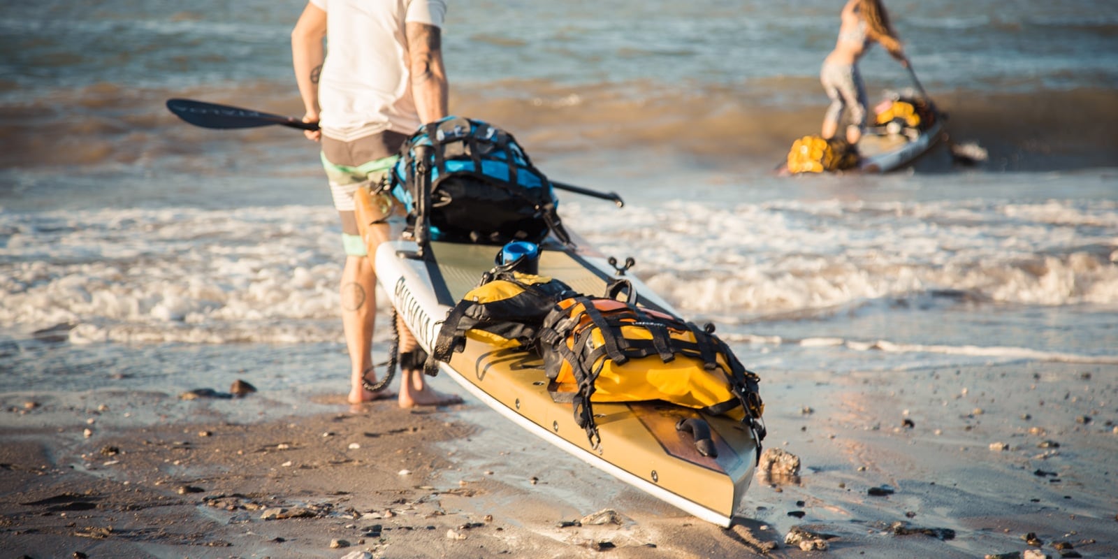 Pulling a kayak across a sandy beach into the water