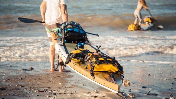 Pulling a kayak across a sandy beach into the water