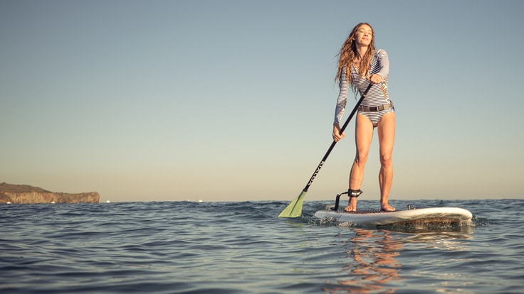 a happy stand up paddle boarder with a strong stroke