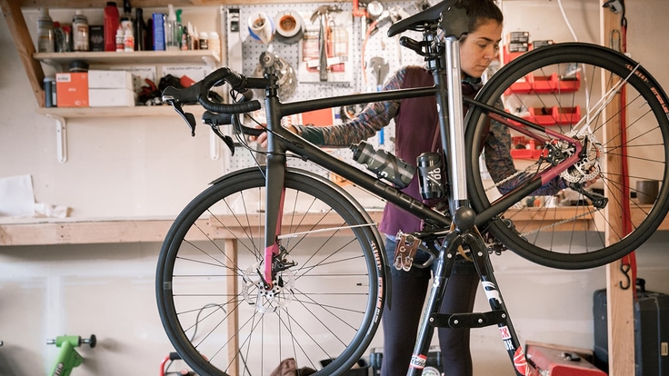 Mounted on a stand, a cyclist inspects her mountain bike in her shop
