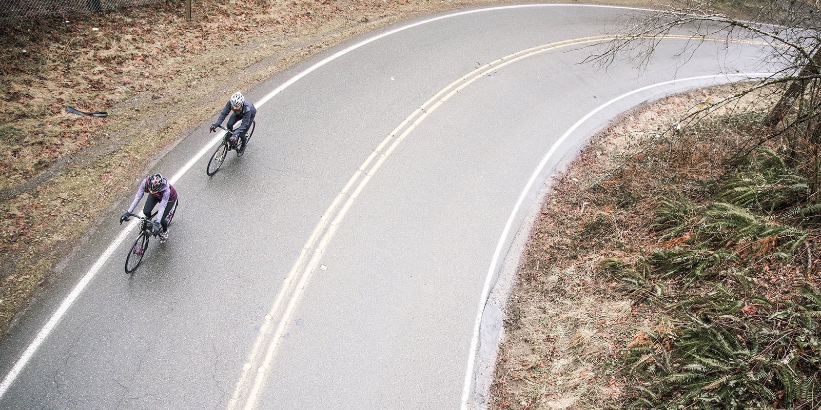 Two cyclists round a curve on the road