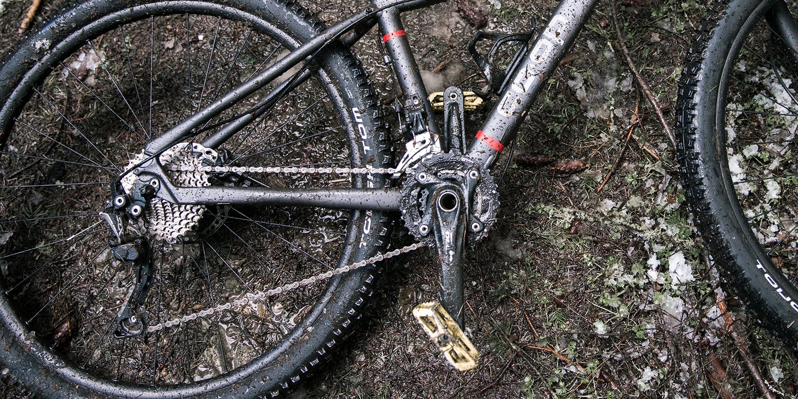 A wet and muddy mountain bike lying on the forest floor