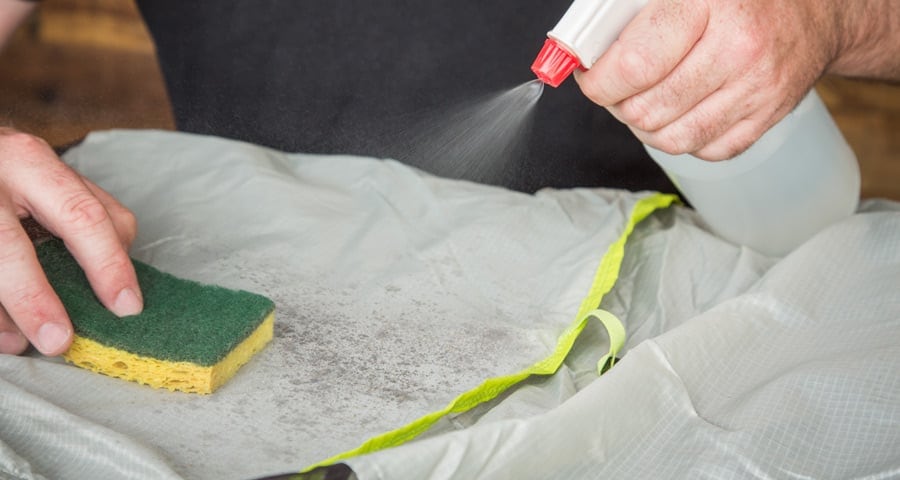 using water and sponge to clean a tent