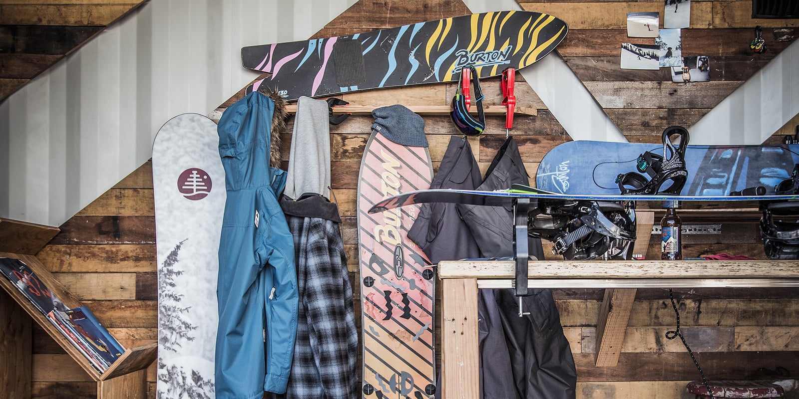 Snowboards on a wood wall and one being repaired