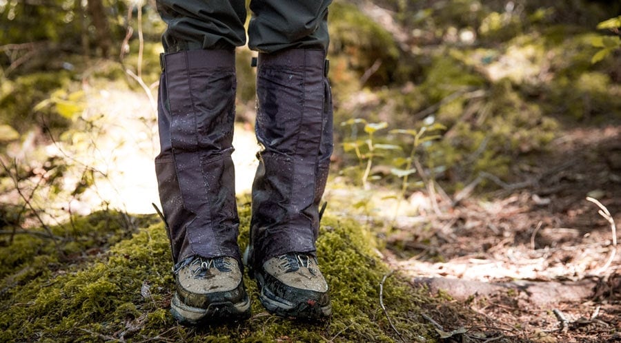 REI Expert Advice: How to Go Backpacking in the Rain - Backpacker gearing up and wearing gaiters for wet weather on the trail