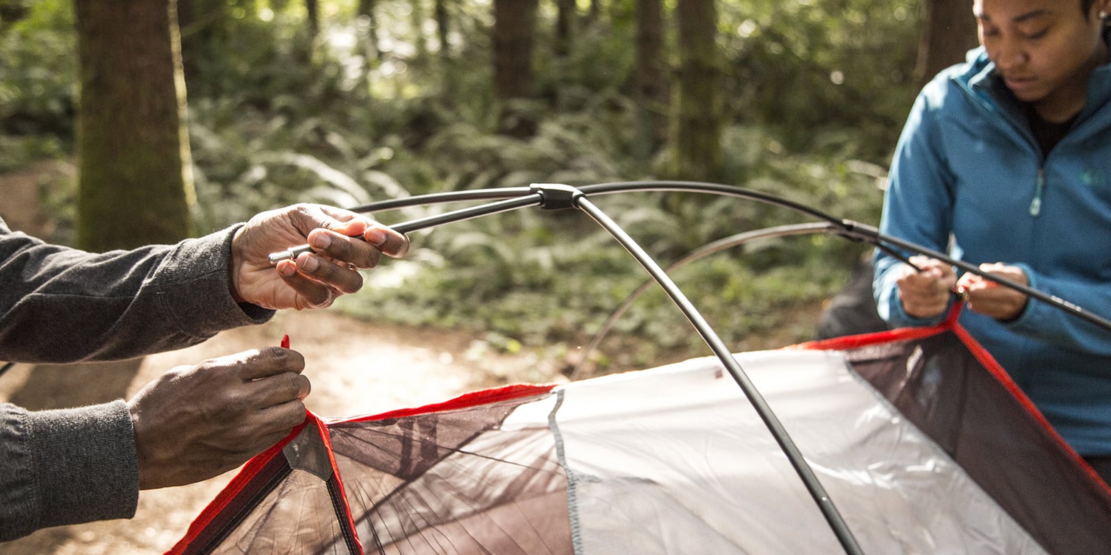 two campers connect tent poles to tent