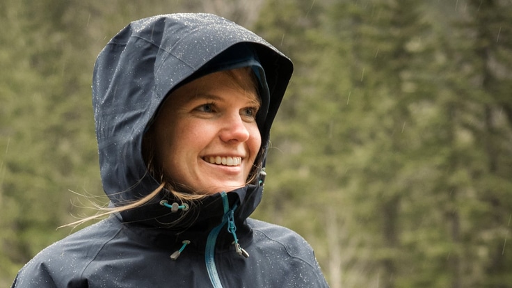A woman wearing a rain jacket while hiking in the rain