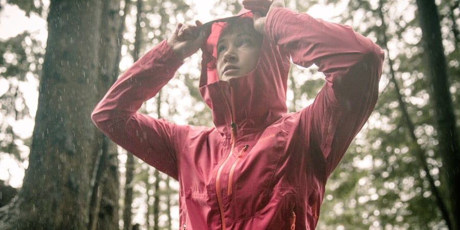 a hiker suiting up with rain gear as the rain starts to fall