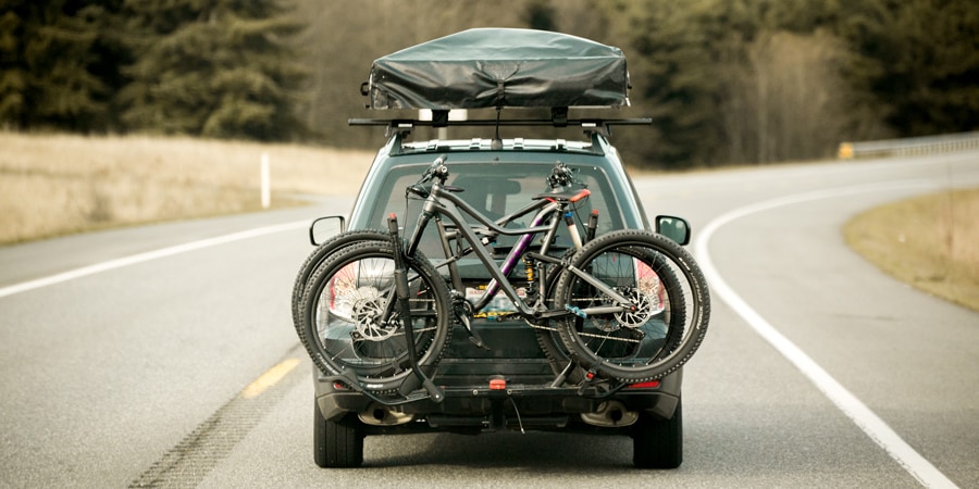 A roof-top tent attached to the roof rack of a driving car