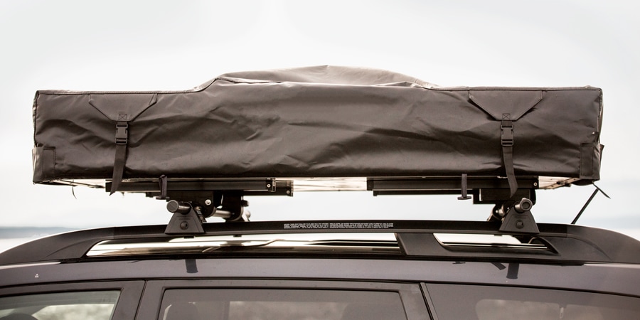 A roof-top tent attached to the roof rack of a car