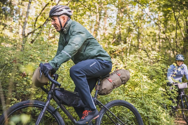 Two people navigate a trail on their mountain bikes wearing pants and jackets