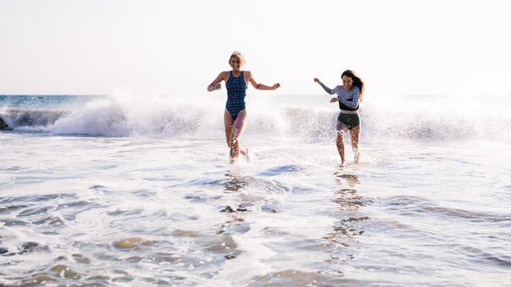 Two women playing in the waves on a sunny day