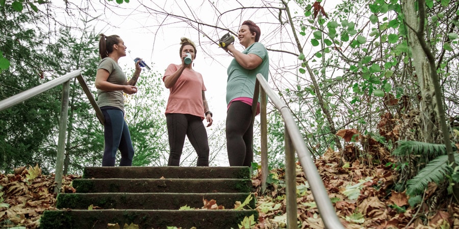 three runners drinking energy drinks at the top of a staircase