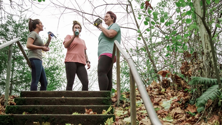 three runners drinking energy drinks at the top of a staircase