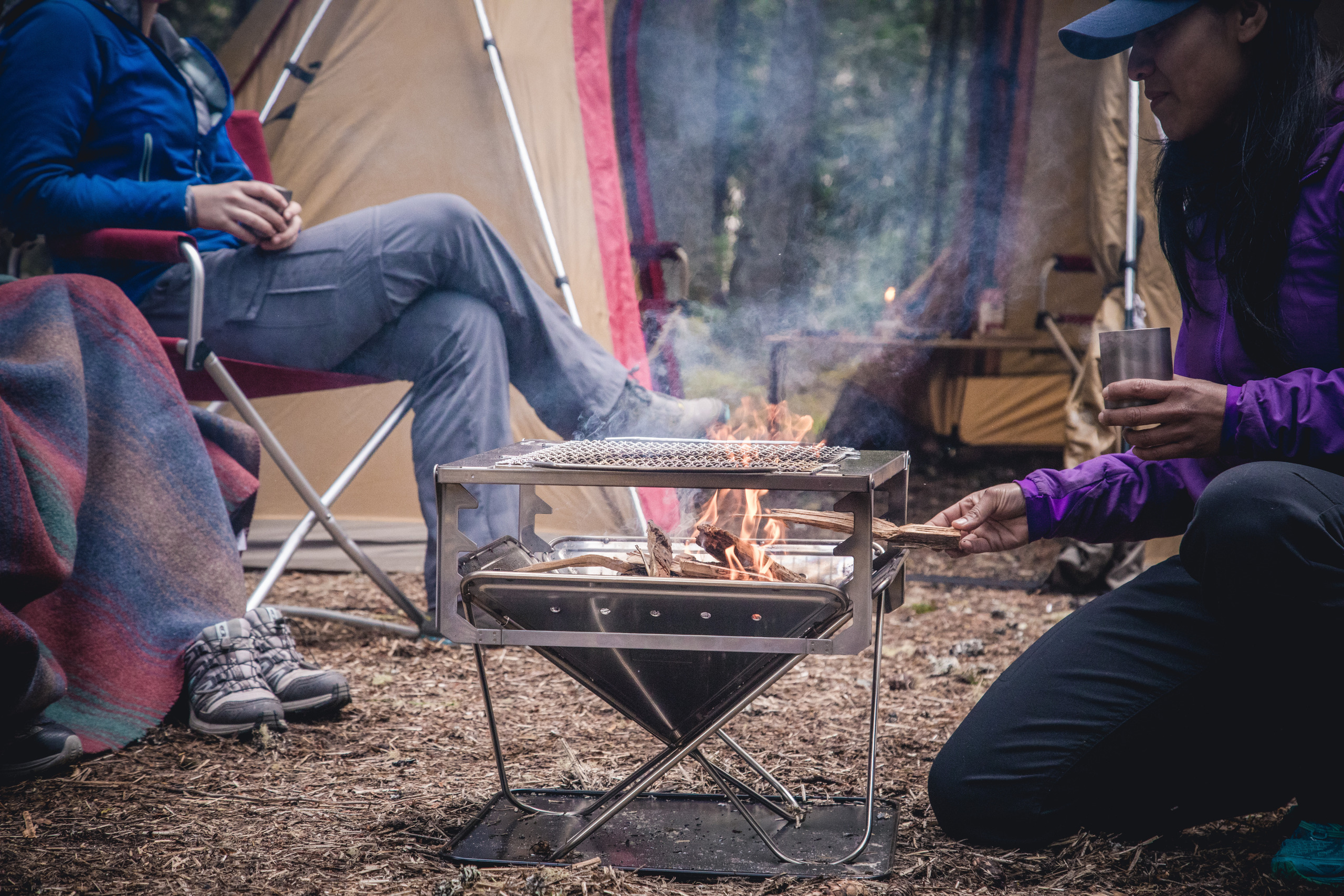 Person feeding a fire at camp
