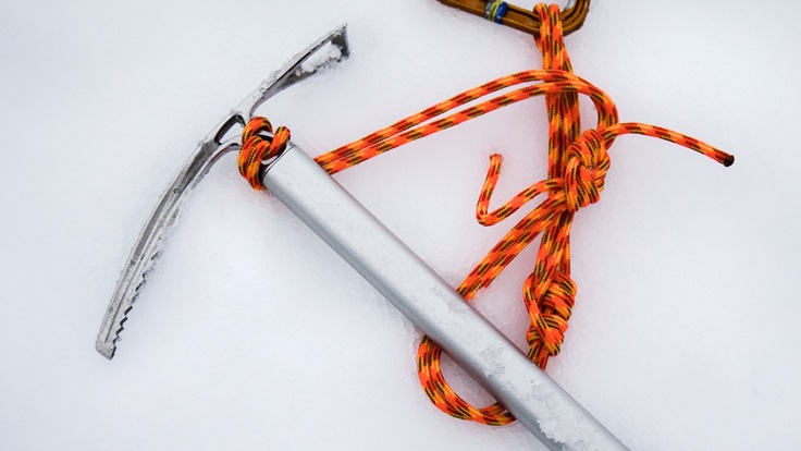 an ice axe, rope, and carabiner on the snow