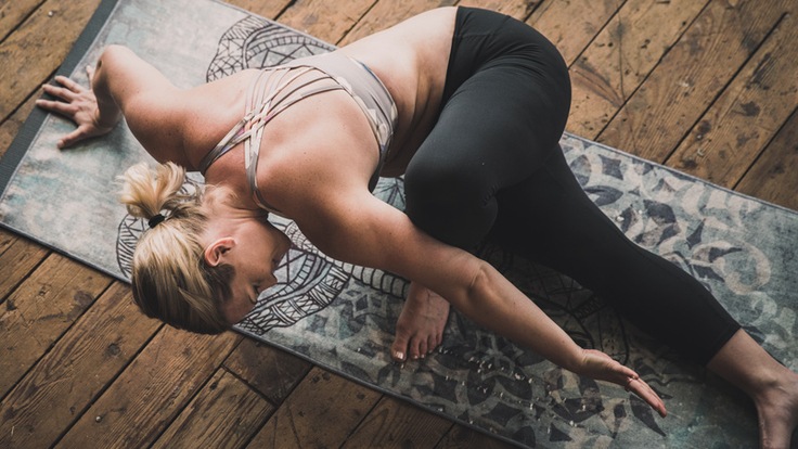 Woman stretches on yoga mat