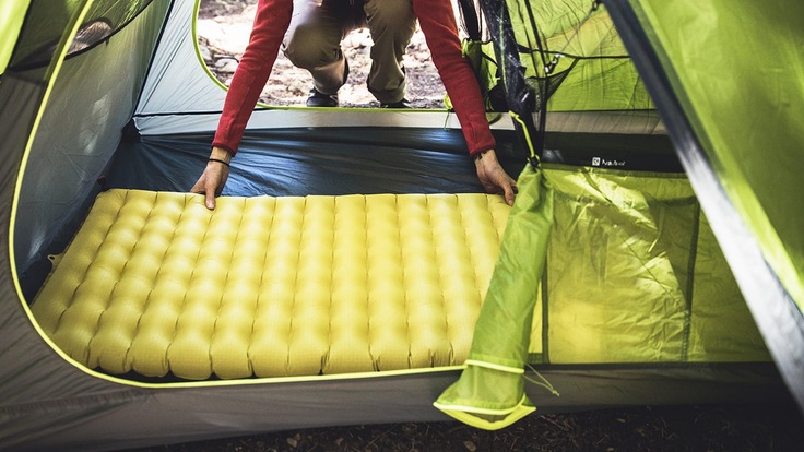 Camper putting sleeping pad into tent