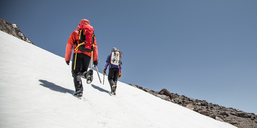 two climbers ascending a steep snowfield