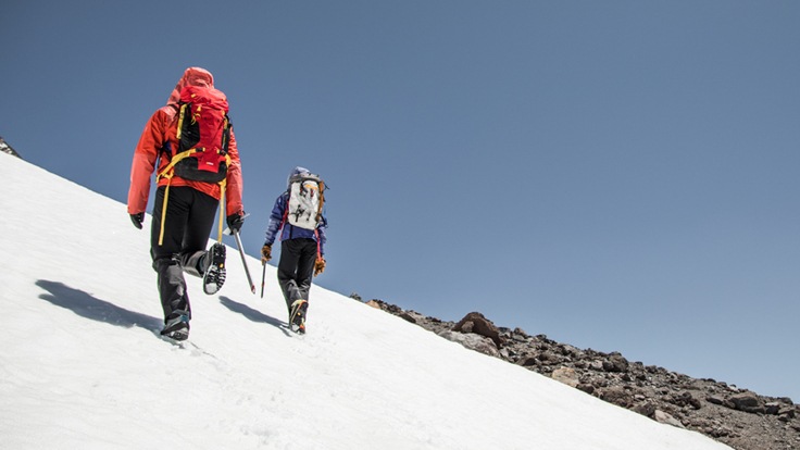 two climbers ascending a steep snowfield