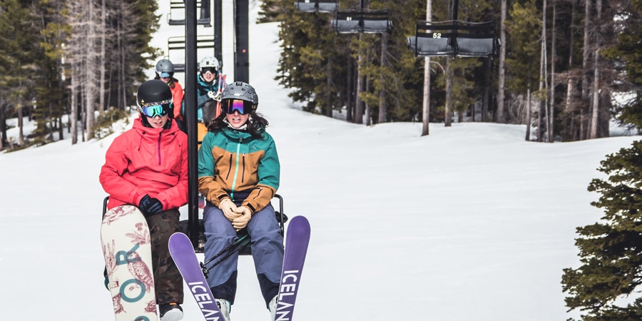 A skier and a snowboarder on a ski lift