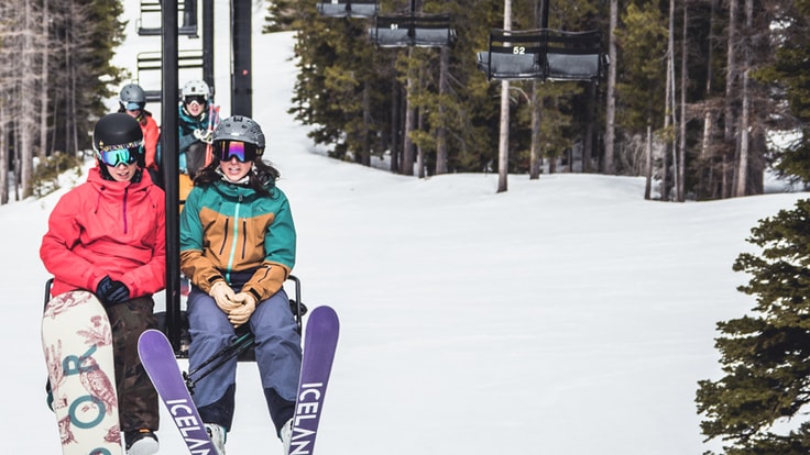 A skier and a snowboarder on a ski lift