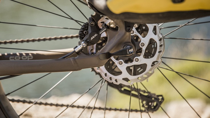 A closeup of the rear wheel of a coop cycle with Shimano components and disc brakes