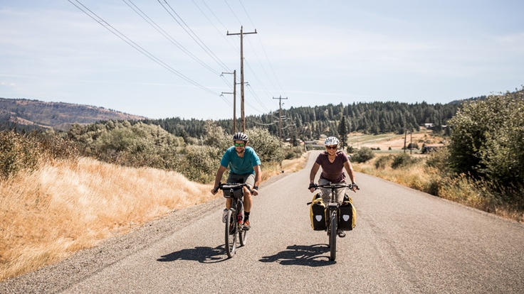 Two people bike touring on a country road