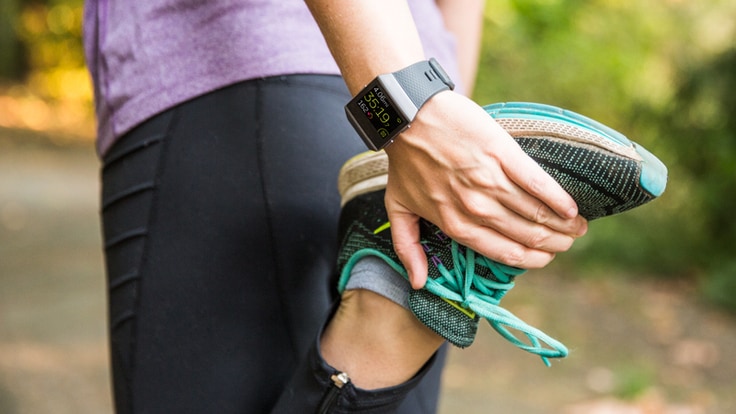 A runner stretches while wearing a fitness watch