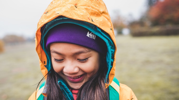 A smiling girl wearing a yellow rain jacket