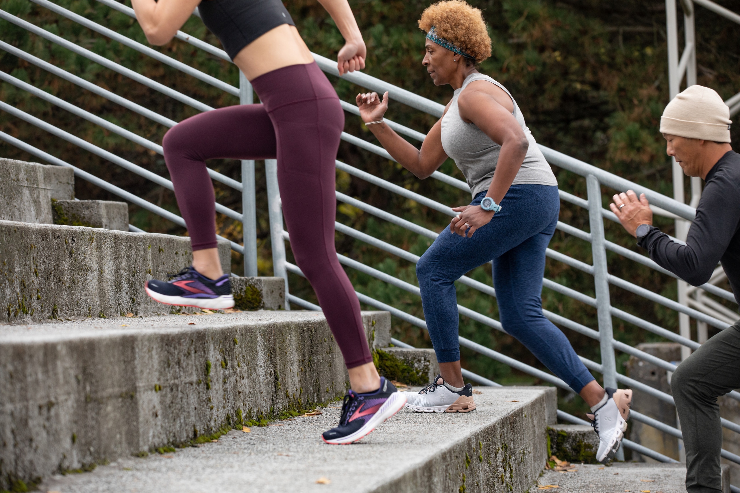 Three people wearing fitness clothing run upstairs