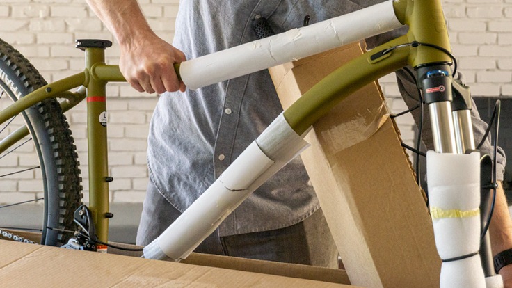A person pulls an unassembled bike out of a box