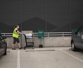 An R E I employee pushes a cart filled with items to a customer's vehicle
