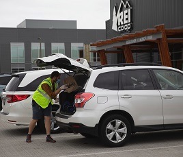 An R E I customer places a bag in the trunk of a customer's vehicle.