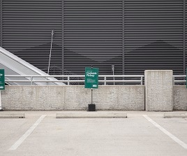 Three empty parking spots outside of an R E I store labeled with green signs that read Curbside Pickup