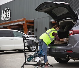 An R E I placing a box in the trunk of a customer's vehicle